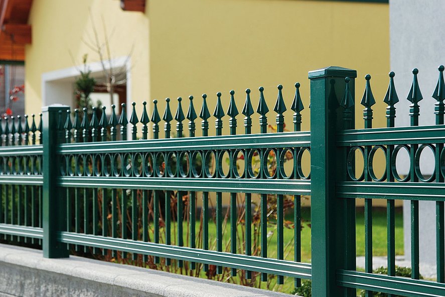 Vue rapprochée d'une clôture à barres couleur vert mousse en aluminium finition ferronnerie d'art avec ornements