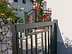 Porte en anthracite en gros plan, derrière une rampe d'escalier également en anthracite, décorée de roses. 