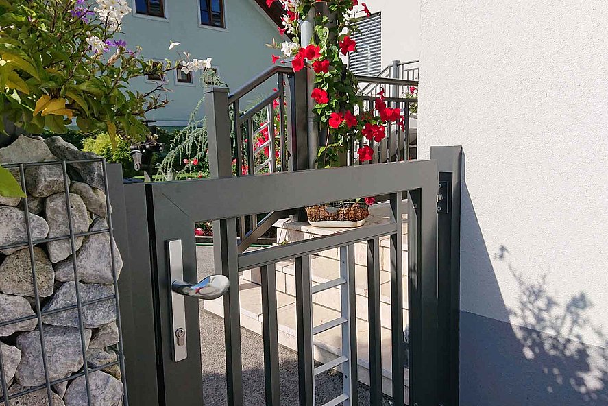 Porte en anthracite et en arrière-plan une rampe d'escalier en anthracite, décorée de roses rouges. 