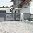 portail électrique à double battant et clôture de jardin en tôle perforée couleur grise devant une grande maison unifamiliale avec garage