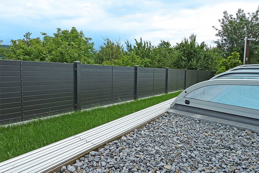 Vue de la piscine couverte dans le jardin sur la clôture de jardin occultante moderne avec des lattes transversales en aluminium
