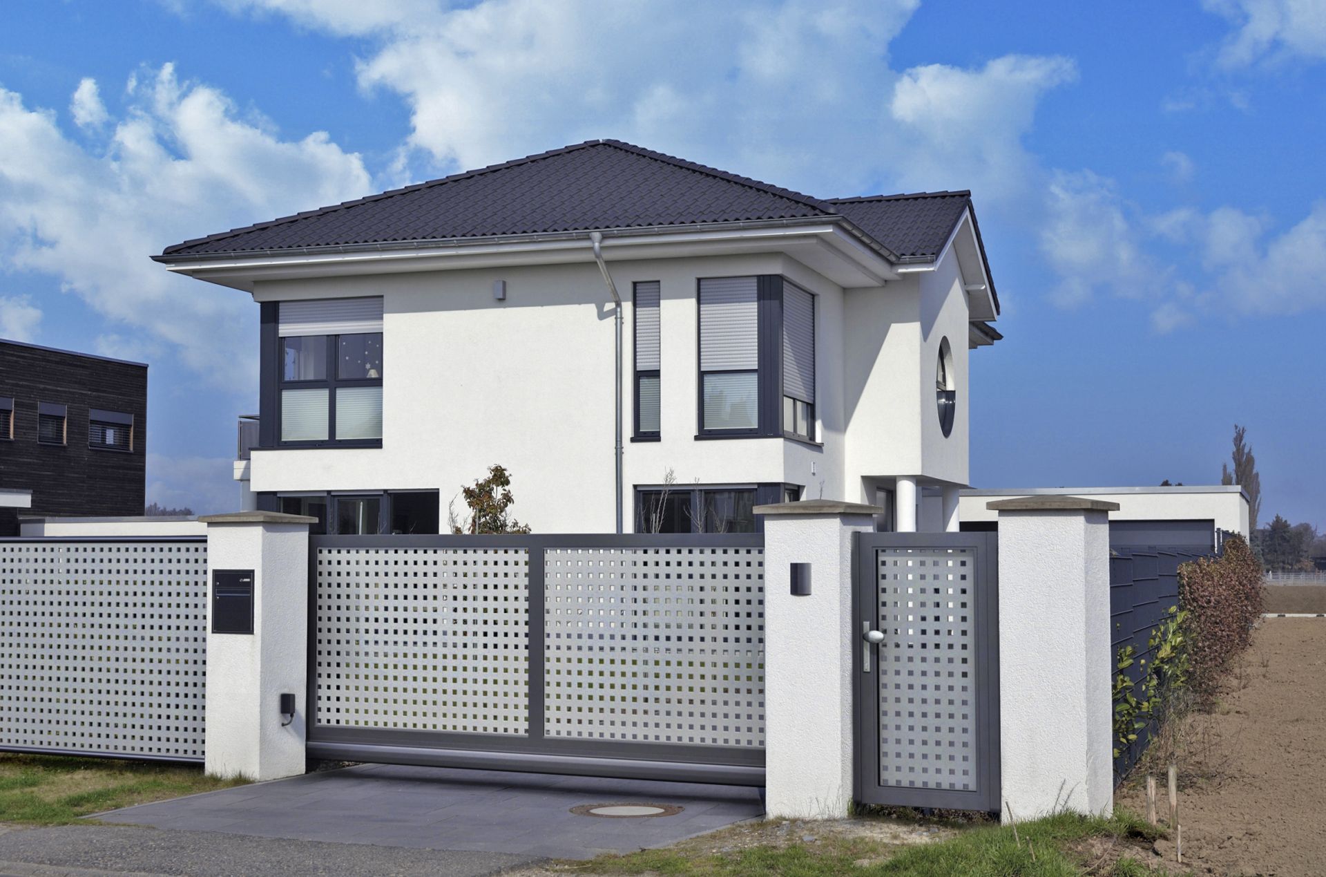 portail coulissant élégant et portillon de jardin bicolore en gris et gris foncé devant une maison individuelle